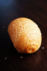 Wheat roll with sesame seeds on dark background