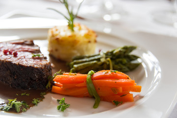 Roasted meat with carrots and asparagus on a white plate