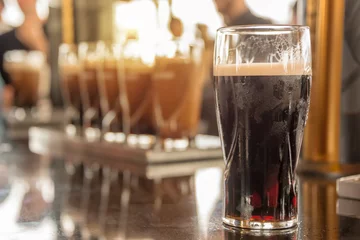 Foto op Plexiglas Close up van een glas stout bier in een bar © Delphotostock