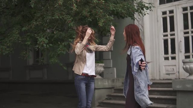 Two red-haired girls are crazy dancing on the street. slow motion