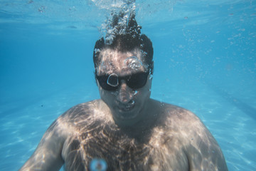 Naklejka premium cool man underwater with sunglasses looking at camera