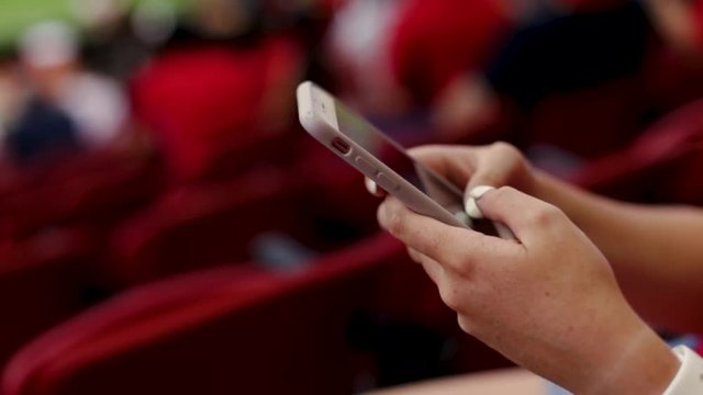 Closeup Of Bored Teen Playing On Smartphone At A Professional Sporting Event In A Stadium - Powered by Adobe