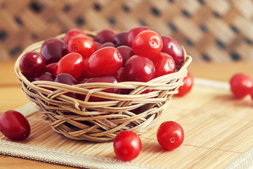 Fresh cornel berries (Cornus mas or Cornelian cherry) in woven basket