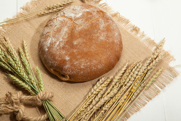 Rustic bread and wheat on a white wooden background