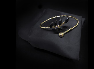 Jewellery black diamonds gold bracelet isolated on black cloth background - obrazy, fototapety, plakaty