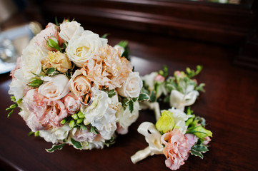Close-up photo of a wedding bouquet and buttonhole flowers laying on the table.