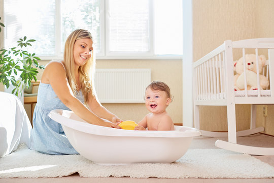 The Mother Bathes The Baby In The Bathroom In The Room.