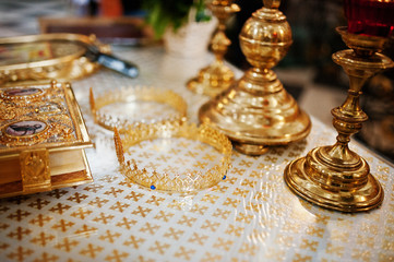 Close-up photo of crowns laying on the table next to the candlesticks and bible in the church.