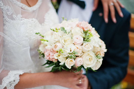Close-up photo of a bride holding a wedding bouquet in her hands.
