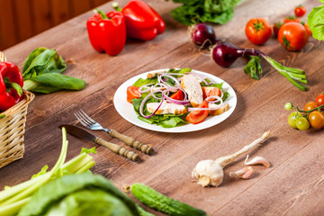 Fresh salad with chicken, tomato and greens on wooden background top view. Healthy food.