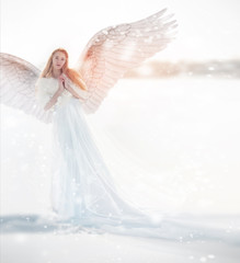 Naklejka premium Woman angel with wings in the winter. Snow angel standing in the snow, the Keeper of winter, a fabulous image