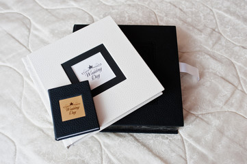 Elegant white and black wedding photobooks or photo albums on the white sofa.