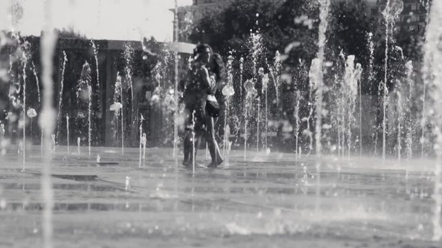 Young happy couple dancing in the fountain