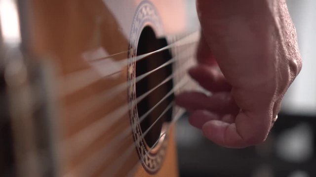 Musician plays acoustic spanish guitar. Close up shot of right hand, shallow depth of field