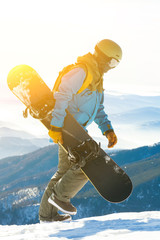 Young snowboarder walking at the top of a mountain