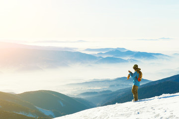 Male snowboarder taking photo of the beautiful landscape from the very top of a mountain