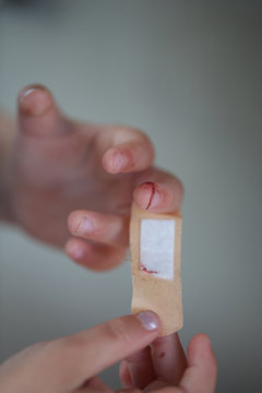 parent applying band aid on finger wound. hands, cut, blood, bandage.
