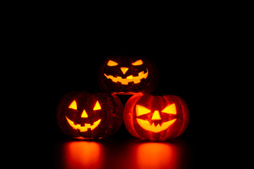 Three spooky carved pumpkins on table in darkness