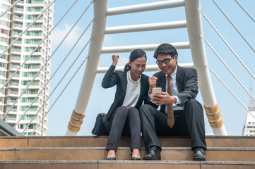 Asian middle business man and woman looking to smart phone feel happy and success with their works.