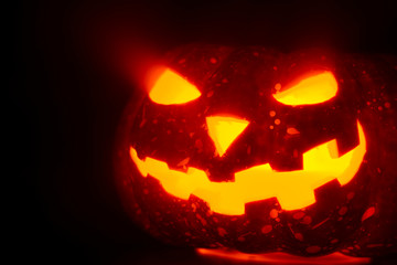Composed glowing carved pumpkin lying on surface in mist