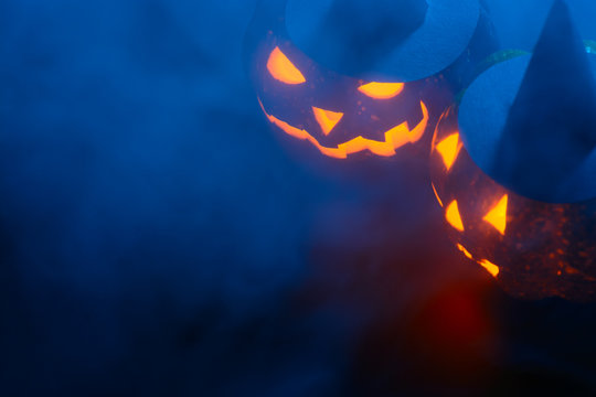 Glowing pumpkins in blue smoke