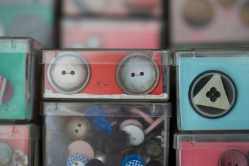 close up of buttons in container. round, plastic, haberdashery, fashion.