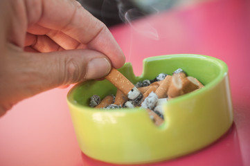 main entrain d'éteindre une cigarette dans un cendrier