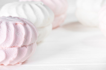 White and pink marshmallows on a white wooden table. Beautiful light background. Food