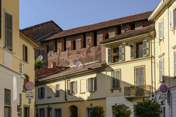 Fototapeta na wymiar castle wall looms over old houses roofs, Vigevano, Italy