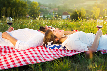 Couple lying on a picnic blanket with glass of wine