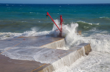 The red crane on the pier with rough sea