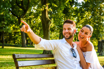 Fototapeta premium Beautiful young couple relaxing on a sunny summer day on a bench