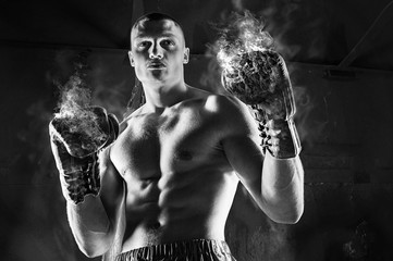 Conceptual Portrait of brutal boxer in fire sparks and smoke.