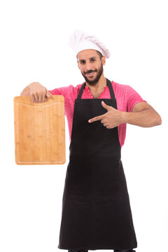 Happy beard chef smiling and holding a wooden cutting board, guy wearing a black chef uniform and chef hat, isolated on white background