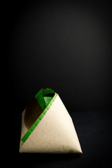 a pack of nasi lemak or Malaysia fragrant rice cooked in coconut milk and pandan leaf, wrapped in banana leaf and paper in black background