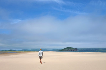 Fototapeta na wymiar Man walking along the sand beach to the sea