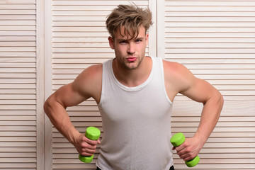 Man holds dumbbells and demonstrates muscles