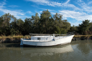Old white boat moored to canal shore