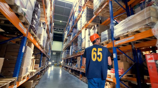 A warehouse worker with a clipboard in back view. 