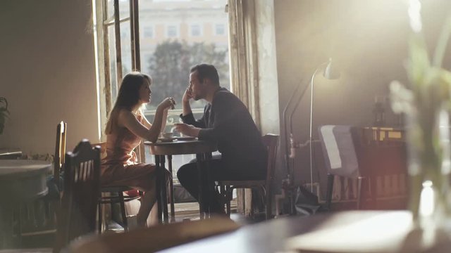 Romantic couple drinking coffee at a cafe table. Happy couple talking in a cafe