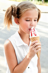 Cute smiling little girl eating an ice cream