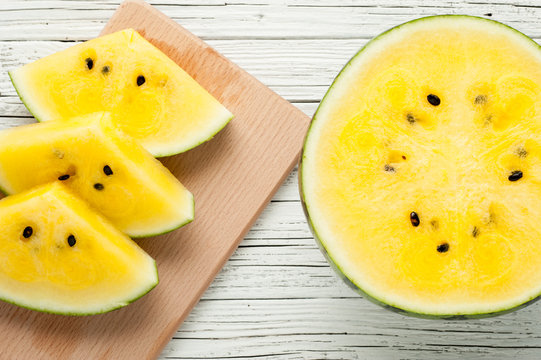 yellow watermelon slices on white wooden background top view