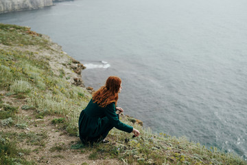 beautiful young woman on the precipice of a mountain near the sea