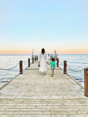 Mom and son walking on a pier to enjoy the sea.