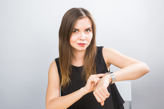 Time is over. Attractive brunette woman pointing to her hand reminding about time