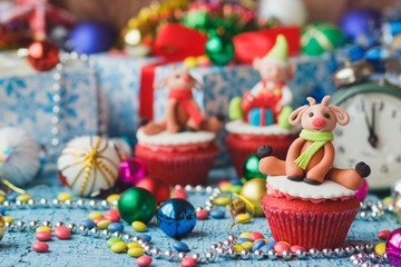 Fototapeta na wymiar Christmas cupcakes with colored decorative deers made from confectionery mastic