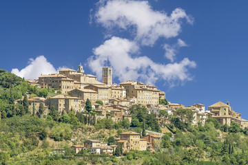 Fototapeta na wymiar Stunning view of the Tuscan hilltop village of Montepulciano, Siena, Italy, on a sunny day with some white clouds