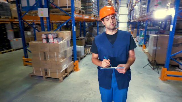 A young serious warehouse inspector works at a storage facility.