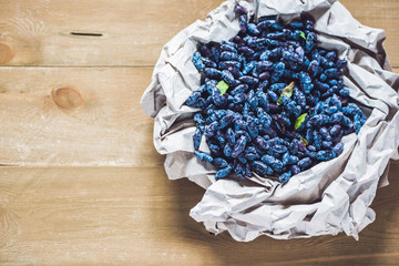 Fresh honeysuckle blue berry fruits with leaf on a wooden background