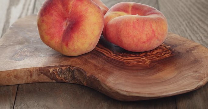 ripe flat peaches on olive board